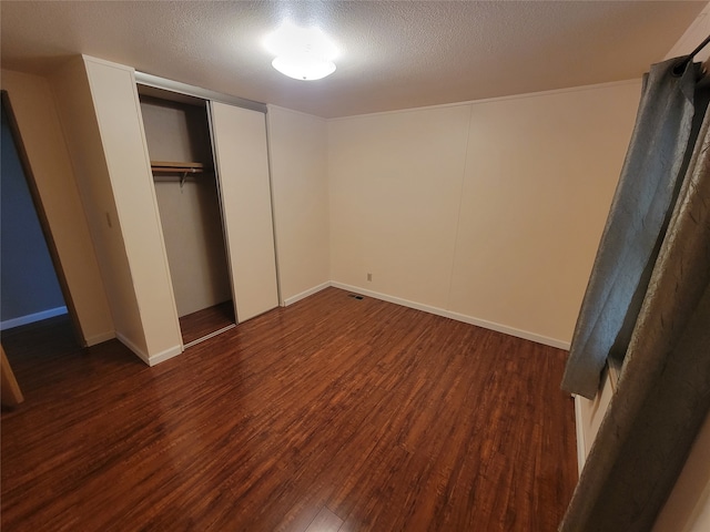 unfurnished bedroom with dark hardwood / wood-style flooring and a textured ceiling