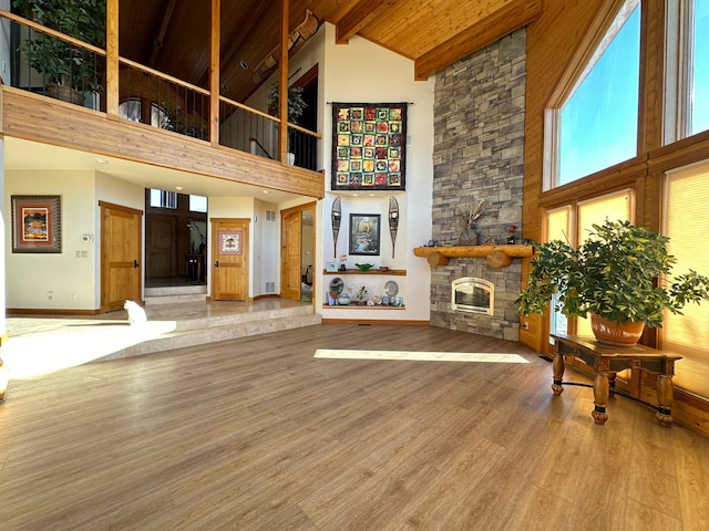 living room with high vaulted ceiling, a fireplace, hardwood / wood-style floors, and beam ceiling