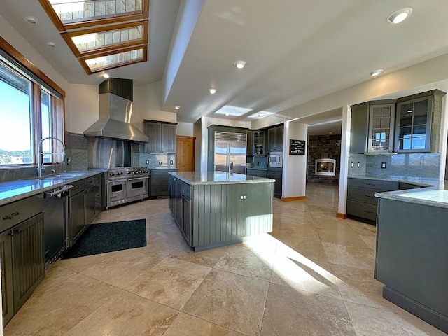 kitchen featuring built in appliances, tasteful backsplash, a kitchen island, and wall chimney range hood