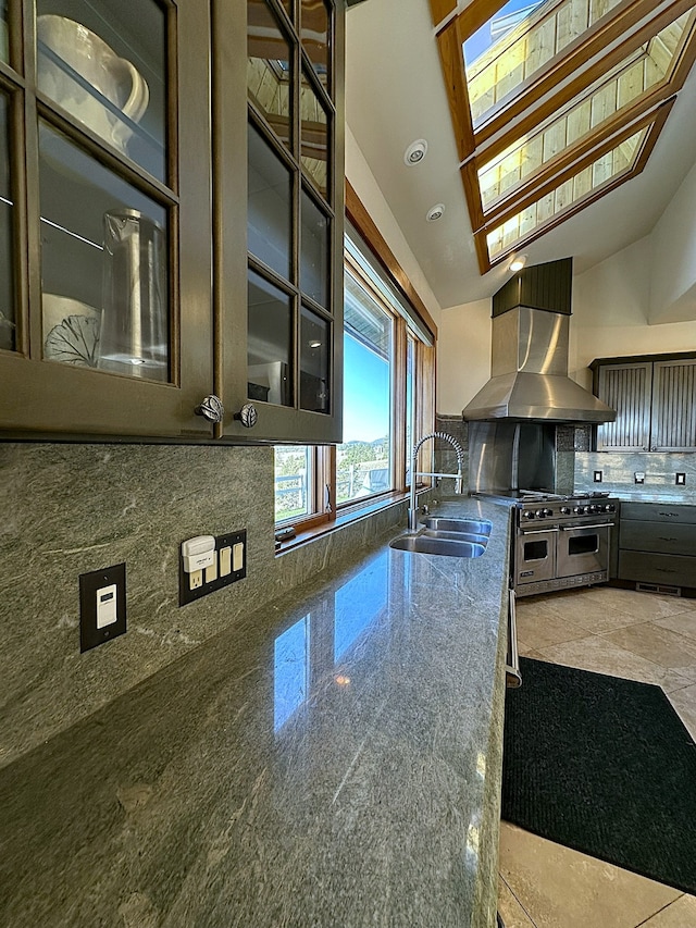 kitchen featuring dark stone counters, sink, tasteful backsplash, a skylight, and island exhaust hood