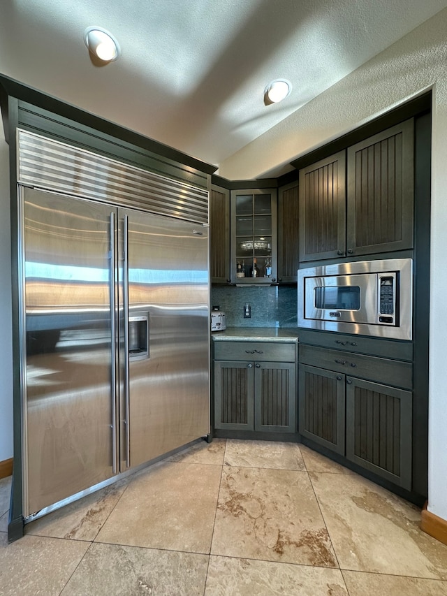 kitchen with built in appliances, dark brown cabinetry, and a textured ceiling