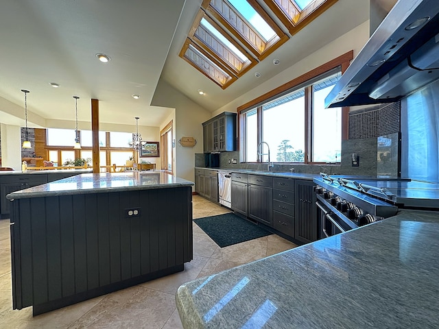 kitchen featuring stainless steel appliances, range hood, a large island, pendant lighting, and lofted ceiling with skylight