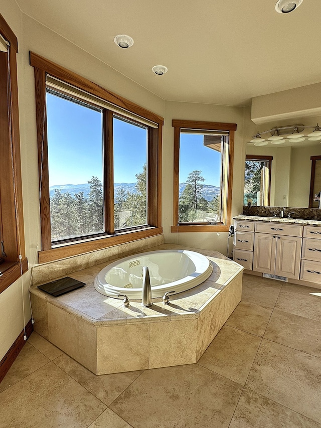 bathroom with tiled bath, vanity, and tile patterned floors