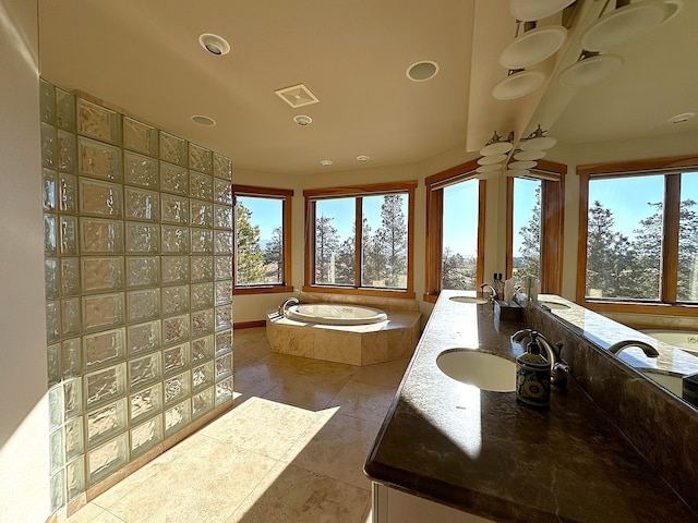 bathroom with vanity, tile patterned flooring, a healthy amount of sunlight, and a relaxing tiled tub