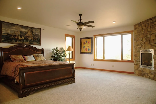 carpeted bedroom featuring a fireplace, ceiling fan, and heating unit