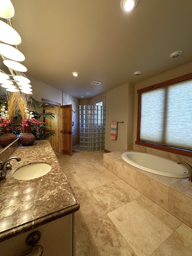 bathroom with tiled bath, vanity, and tile patterned floors