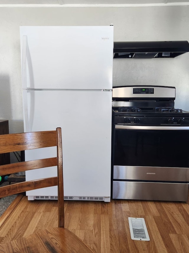 kitchen with hardwood / wood-style flooring, stainless steel range with gas stovetop, white fridge, and exhaust hood