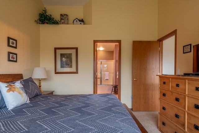 bedroom featuring ensuite bathroom, a towering ceiling, and carpet floors