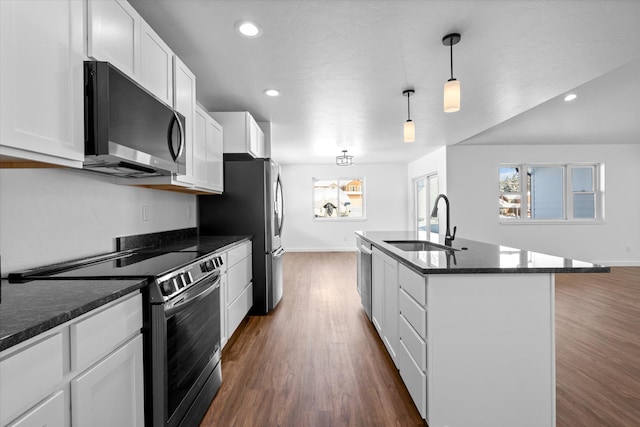 kitchen with an island with sink, stainless steel appliances, decorative light fixtures, sink, and white cabinets