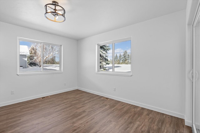 unfurnished bedroom with multiple windows, a notable chandelier, and dark hardwood / wood-style flooring