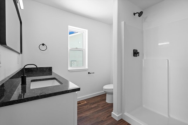 bathroom featuring hardwood / wood-style flooring, vanity, toilet, and walk in shower