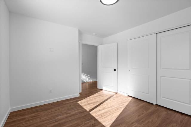 unfurnished bedroom featuring a closet and dark hardwood / wood-style flooring