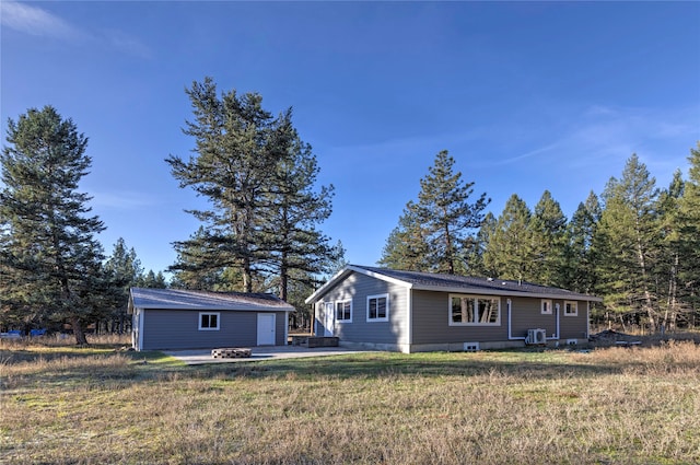 back of property featuring a garage, an outbuilding, and a lawn