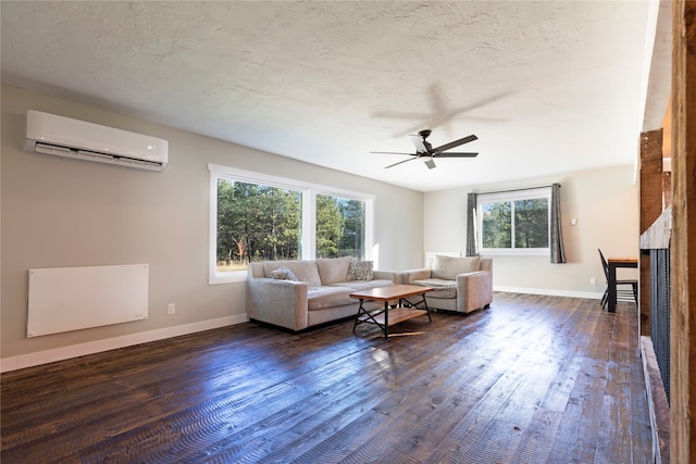 living room featuring dark wood-type flooring, ceiling fan, a wall unit AC, and a textured ceiling