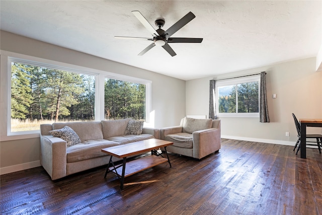 living room featuring dark wood-type flooring, ceiling fan, and plenty of natural light