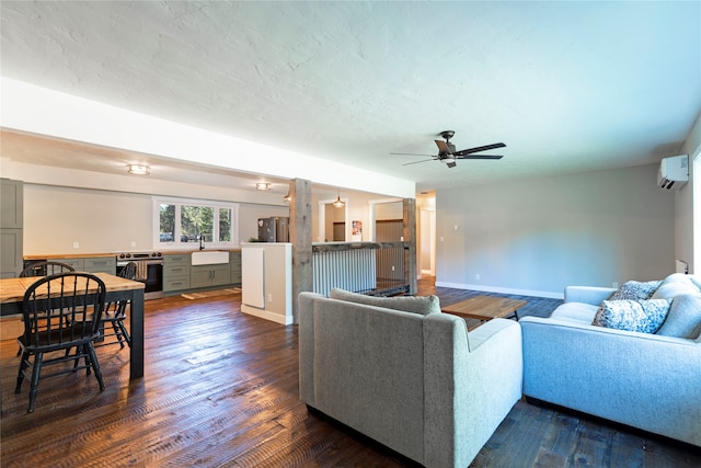 living room featuring an AC wall unit, dark hardwood / wood-style floors, built in desk, sink, and a textured ceiling