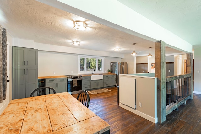 kitchen with pendant lighting, appliances with stainless steel finishes, dark hardwood / wood-style floors, wine cooler, and a textured ceiling