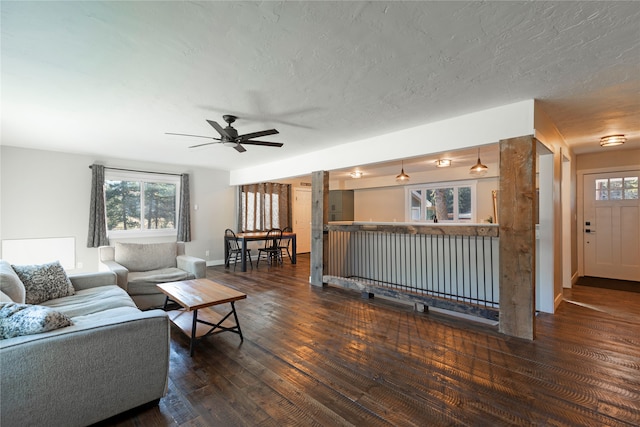 living room featuring ceiling fan, dark hardwood / wood-style floors, and a textured ceiling