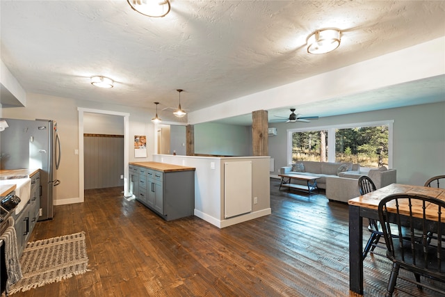 kitchen with wood counters, gray cabinetry, stainless steel fridge, dark wood-type flooring, and a textured ceiling