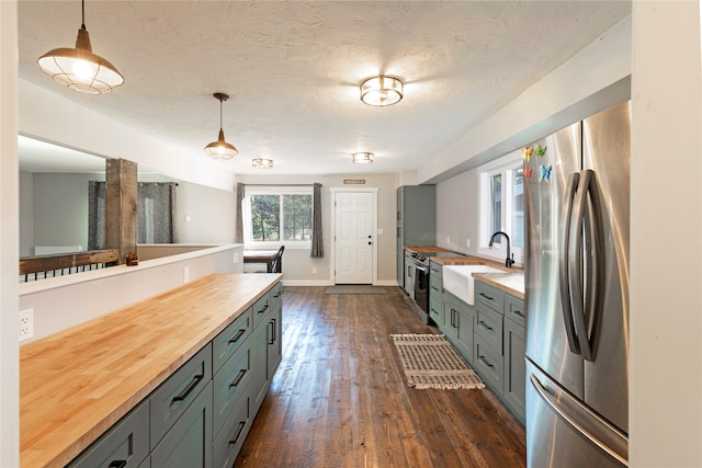 kitchen with pendant lighting, wood counters, appliances with stainless steel finishes, and sink