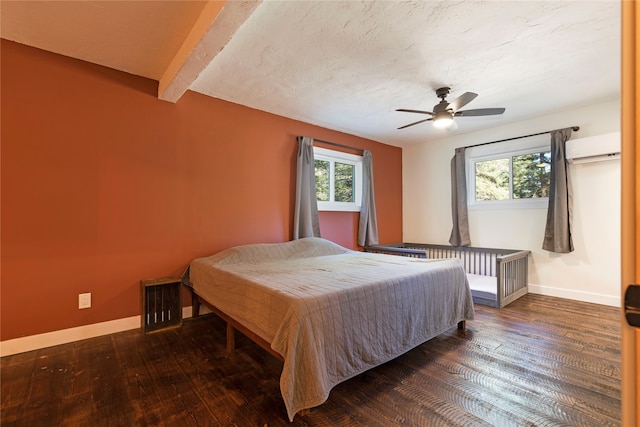 bedroom featuring dark wood-type flooring, ceiling fan, beam ceiling, a wall unit AC, and a textured ceiling