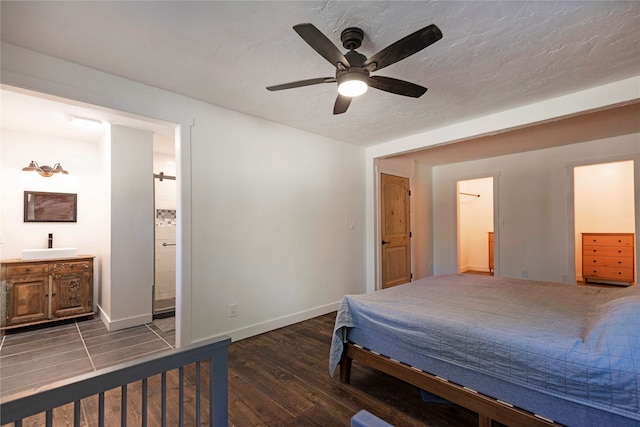 bedroom featuring dark hardwood / wood-style floors, ceiling fan, connected bathroom, and a textured ceiling