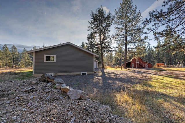 view of side of home featuring a mountain view and an outdoor structure