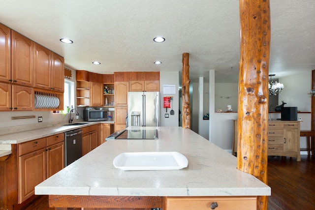 kitchen featuring sink, dark hardwood / wood-style floors, a textured ceiling, a kitchen island, and stainless steel appliances