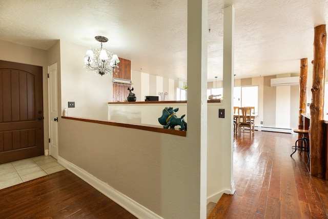 interior space with a textured ceiling, hardwood / wood-style flooring, baseboard heating, and a notable chandelier