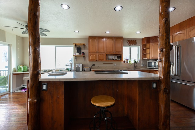 kitchen with dark wood-type flooring, sink, a textured ceiling, appliances with stainless steel finishes, and a breakfast bar area