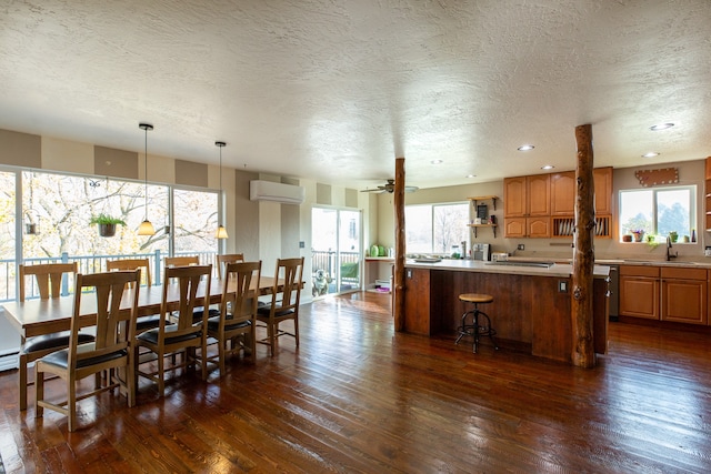 dining space featuring ceiling fan, sink, a wall mounted air conditioner, dark hardwood / wood-style flooring, and a textured ceiling