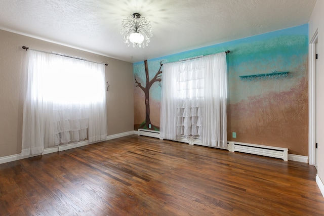 spare room featuring dark hardwood / wood-style floors, baseboard heating, and a notable chandelier