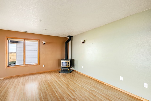 451 1st Rd NE, Fairfield, MT 59436 - unfurnished living room with a wood stove, wood finished floors, and a textured ceiling