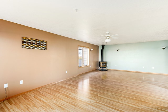 451 1st Rd NE, Fairfield, MT 59436 - unfurnished living room featuring light wood-style floors, a wood stove, and a ceiling fan