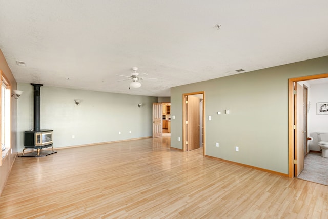 451 1st Rd NE, Fairfield, MT 59436 - unfurnished living room with a wood stove, a ceiling fan, and light wood-type flooring