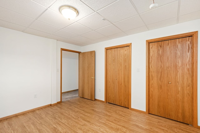 451 1st Rd NE, Fairfield, MT 59436 - unfurnished bedroom featuring a drop ceiling, light wood-style flooring, and two closets