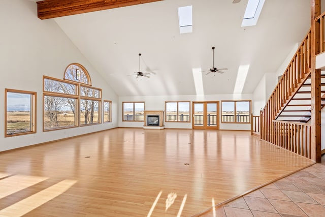 451 1st Rd NE, Fairfield, MT 59436 - unfurnished living room with high vaulted ceiling, a skylight, a ceiling fan, light wood-style floors, and beamed ceiling