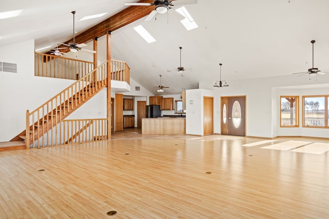 451 1st Rd NE, Fairfield, MT 59436 - unfurnished living room featuring ceiling fan, high vaulted ceiling, a skylight, light wood finished floors, and stairway