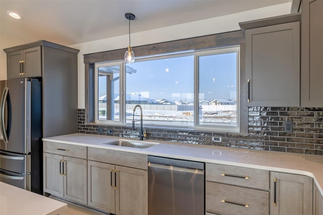 kitchen with pendant lighting, stainless steel appliances, sink, backsplash, and gray cabinets