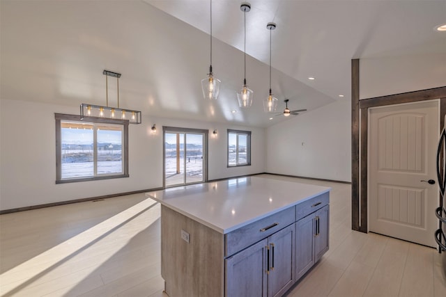 kitchen featuring ceiling fan, vaulted ceiling, hanging light fixtures, and a center island