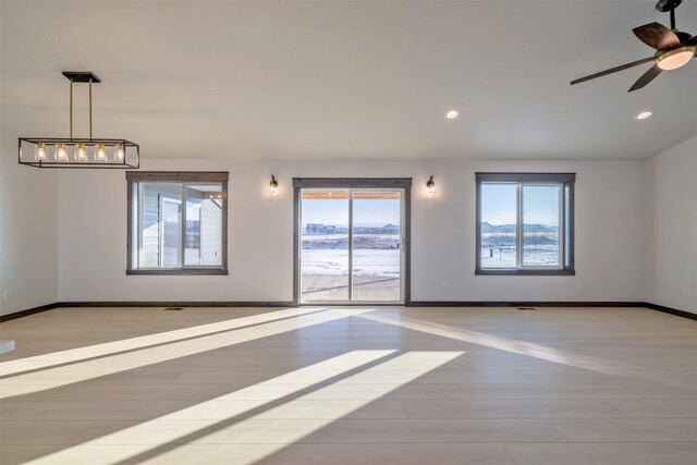 empty room with ceiling fan and light hardwood / wood-style flooring