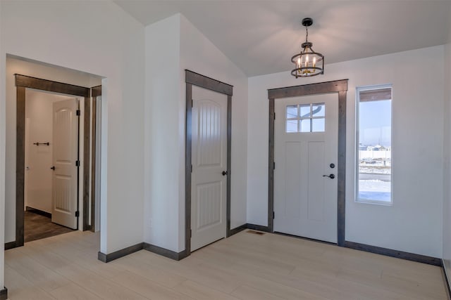 entrance foyer featuring lofted ceiling, a notable chandelier, and light wood-type flooring