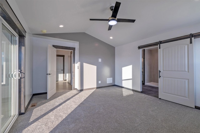 unfurnished bedroom with ceiling fan, a barn door, light colored carpet, and multiple windows