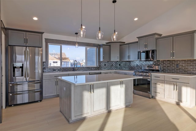 kitchen featuring tasteful backsplash, lofted ceiling, stainless steel appliances, and a kitchen island