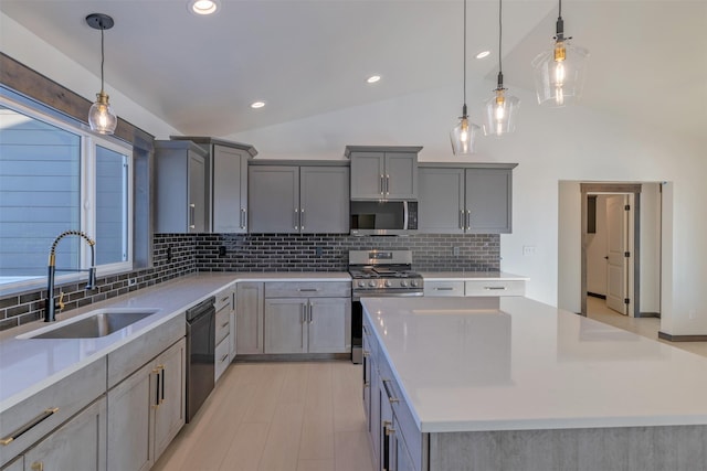 kitchen with sink, pendant lighting, appliances with stainless steel finishes, and a kitchen island