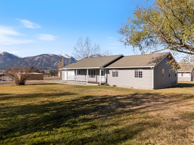 rear view of property featuring a mountain view, a yard, and a porch