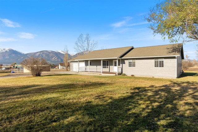 back of house with a mountain view, a garage, covered porch, and a yard