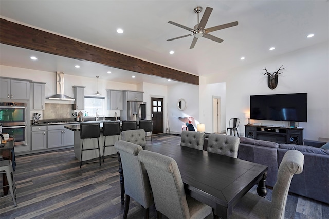 dining area featuring ceiling fan, sink, dark hardwood / wood-style floors, and beamed ceiling