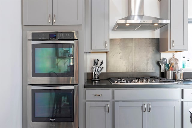 kitchen with stainless steel appliances, wall chimney exhaust hood, and decorative backsplash