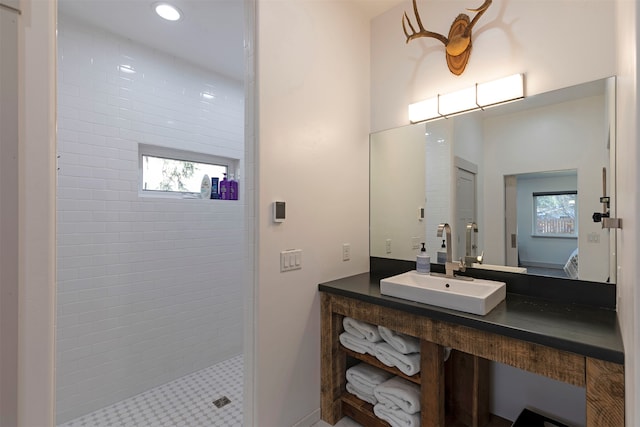 bathroom with a wealth of natural light, vanity, and a tile shower